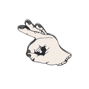 Detail shot of OK hand gesture enamel pin with black and white minimalist design