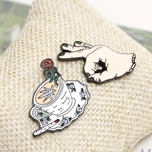 Close-up of rose coffee cup and OK gesture hand enamel pins with black nickel finish