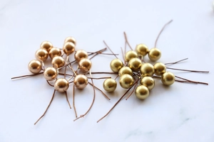Close-up of 10mm gold and copper metallic berries with wire stems for DIY Christmas crafts