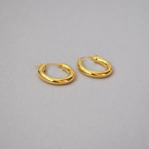 Macro shot of minimalist gold plated chunky hoop earrings with high polish metal finish