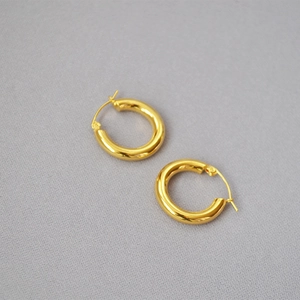 Detail of chunky gold-plated brass hoop earrings with mirror-like polished finish