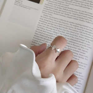 Detailed close-up of an adjustable silver star ring worn on a finger over artistic book pages