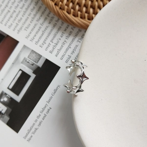 Macro detail of silver star-shaped adjustable ring on a white ceramic display plate