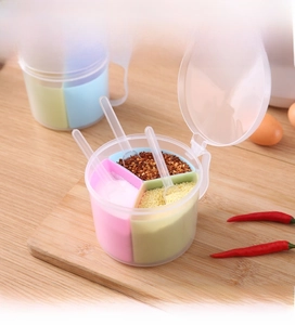 Close-up of three-compartment round seasoning box with transparent lid and small spoons