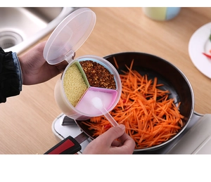 Close-up of a 4-compartment kitchen spice box with spoons in a natural home setting