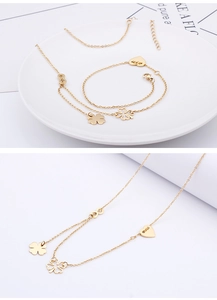 Detail of gold clover and heart jewelry set featuring thin chain necklace and bracelet