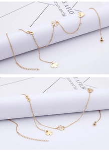 Detailed view of gold chain anklet featuring infinity, clover, and heart charms on white