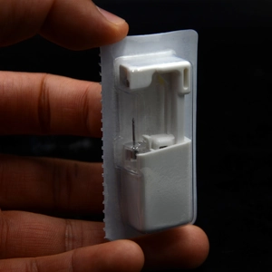Detail view of a disposable ear piercing tool with crown stud in sterile packaging
