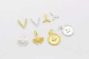 Macro detail of S925 sterling silver charms including fish tail and V-shape pendants