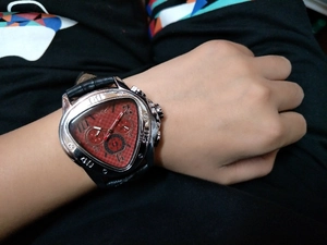 Wrist shot of a men's triangular automatic watch featuring a red carbon fiber dial