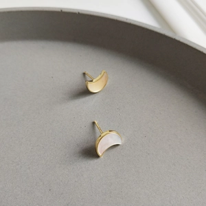 Minimalist 925 silver moon earrings with shell inlay on a grey ceramic plate