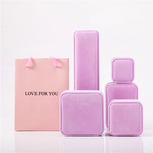 Elegant purple velvet jewelry boxes and pink paper gift bag set on white background