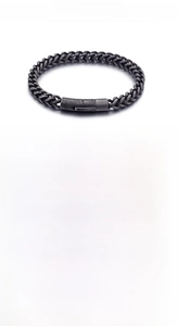 Detalle de una pulsera trenzada de acero inoxidable con textura de metal vintage y cierre