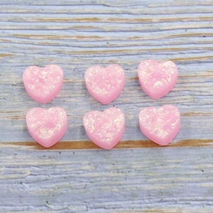 Pack of six pink resin heart-shaped opal beads for DIY jewelry making on wooden background