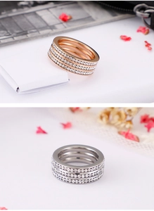 Macro view of triple-row zircon rings in rose gold and silver finishes on a floral background
