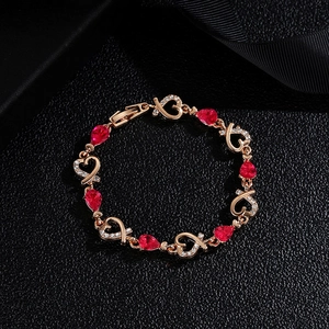 Macro shot of rose gold heart bracelet with red pear-cut stones and diamonds