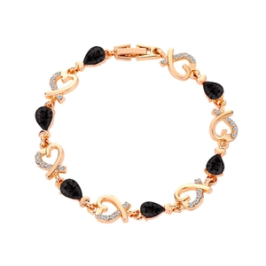 Detailed close-up of golden heart bracelet with black teardrop crystals and white zircon