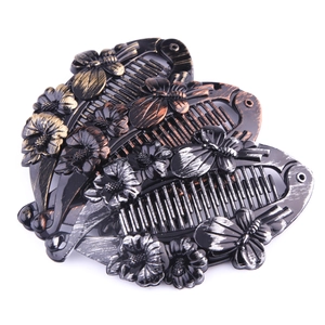 Detailed view of large matte banana hair clips with embossed metallic flowers and butterflies