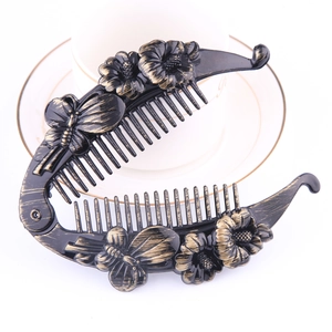 Detail of banana hair clip featuring gold painted 3D floral and butterfly patterns
