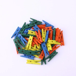 Close-up of vibrant multicolored wooden mini pegs stacked on a clean white surface
