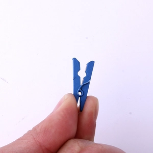 Blue mini wooden clothespin held by hand for scale, perfect for crafts and decor