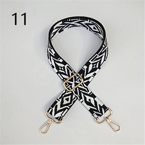 Close-up of black and white geometric woven wide strap with gold metal hooks and buckles