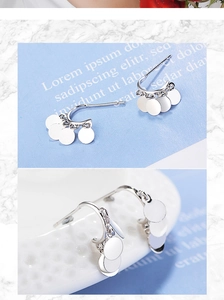 Detail of silver drop earrings with polished round charms on a bohemian half-hoop design