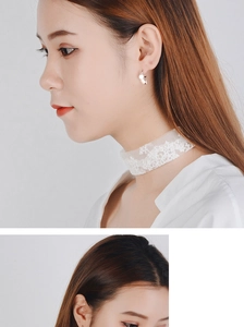 Close-up of elegant silver round stud earrings and white floral lace choker on a model