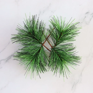 Macro view of artificial pine branches with green needles on white marble background