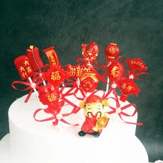 Detail of red Chinese New Year cake toppers set with God of Wealth figurine on white cake