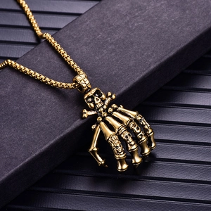 Macro shot of punk style golden skull hand skeleton pendant with matching box chain