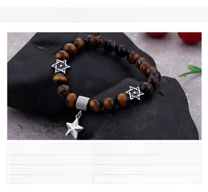 Macro shot of brown tiger eye bead bracelet with stainless steel star charms on dark rock