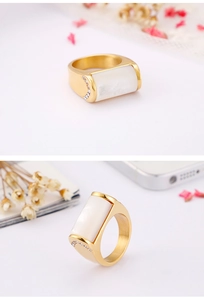 Detail of wide gold titanium ring with rectangular shell inlay and zircon accents