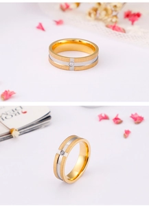 Detail of brushed gold and silver stainless steel ring with a single clear zircon stone