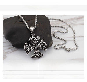 Detail of a vintage stainless steel Celtic cross pendant on a textured dark stone background
