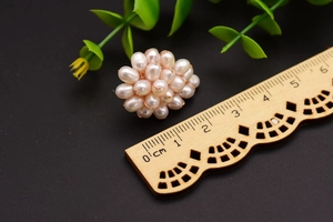 Detailed view of floral pearl earrings with size scale showing 2cm diameter on dark background
