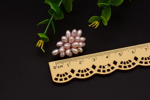 Macro shot of 2.5cm pink pearl cluster jewelry with green leaf on black background