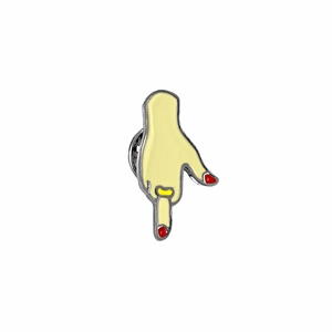 Macro shot of yellow hand enamel pin with red nail polish and gold ring detail