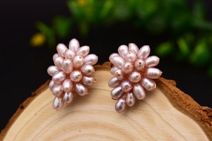 Macro shot of cluster pearl earrings in mauve grape shape on a natural wooden background