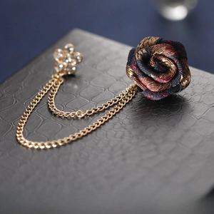 Macro detail of mixed-color silk rose brooch with diamond pin and golden chains