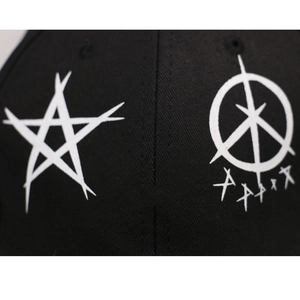 Détail de la casquette noire en coton avec étoile graffiti blanche et anneau en métal punk