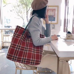Classic red plaid canvas tote bag with leather straps for women in a cafe setting