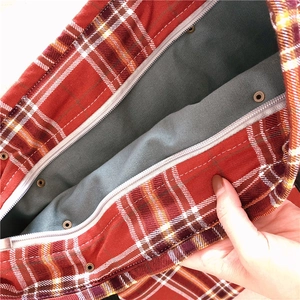 Detailed close-up of the red plaid tote bag interior with zipper and metal snap buttons