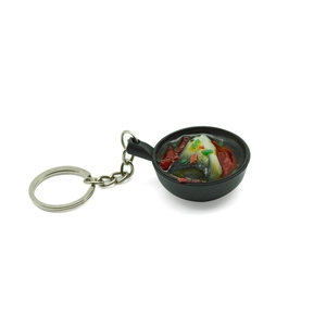 Creative PVC miniature fish head stew food keychain on white background