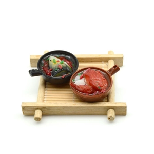 Macro detail of miniature PVC claypot rice food models on a tiny bamboo tray