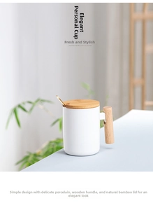 Close-up of white ceramic mug with wooden handle, bamboo lid and golden spoon on a table