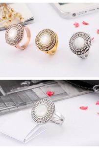 Close-up of double-row rhinestone ring with white opal stone in gold, silver, and rose gold