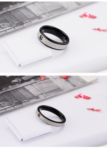 Close-up of matte black and silver steel rings with a single square zircon inlay