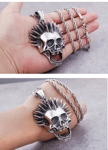 Detailed close-up of a silver punk skull pendant with spiked hair on a twisted chain