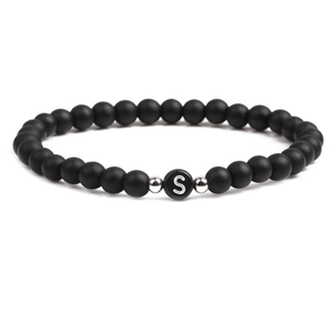 Detailed close-up of 6mm matte black stone beads with silver spacers and letter S bead